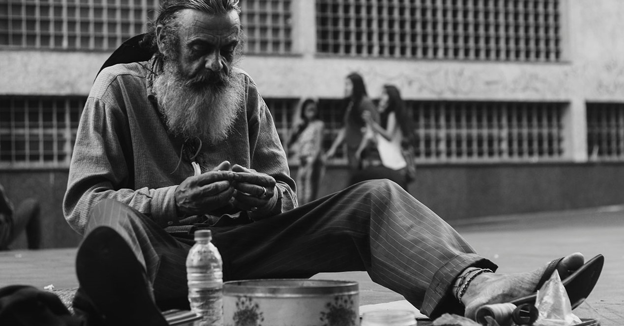 Bilde av en hjemløs mann på et fortau.