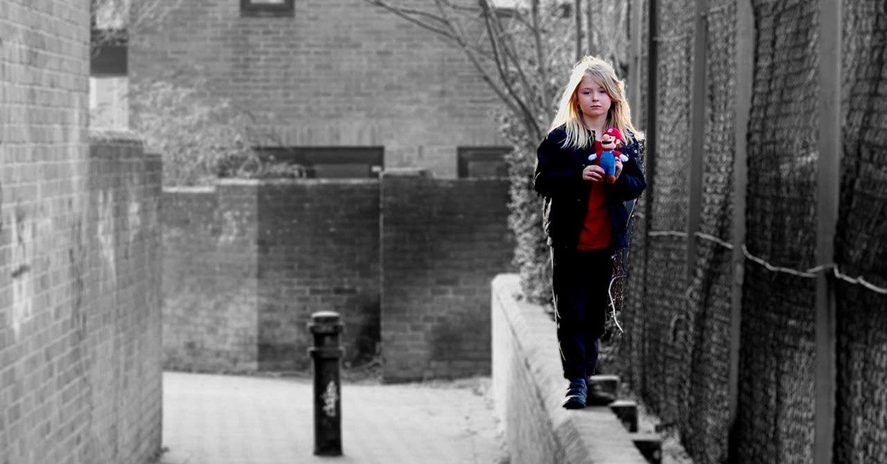 Mollstemt foto av lita jente som balanserer på en murkant.