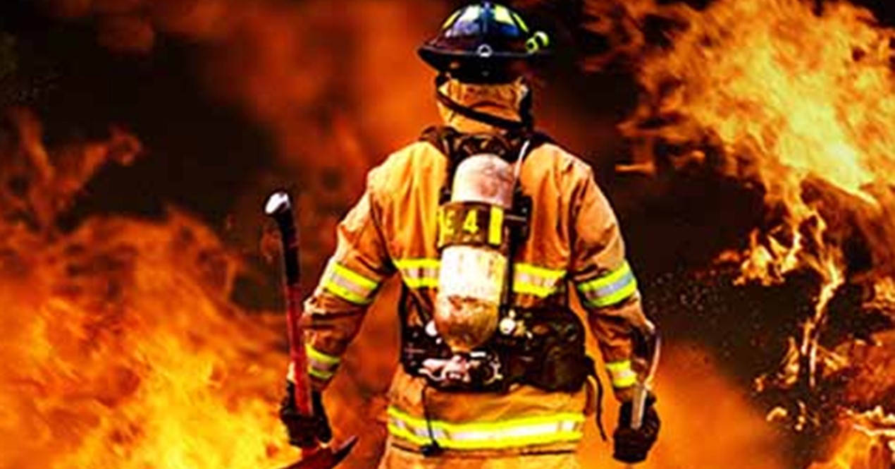 Brannmann i forgrunnen som ser ut mot flammende brann