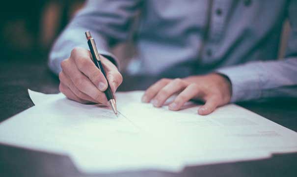 En person skriver under en leiekontrakt
