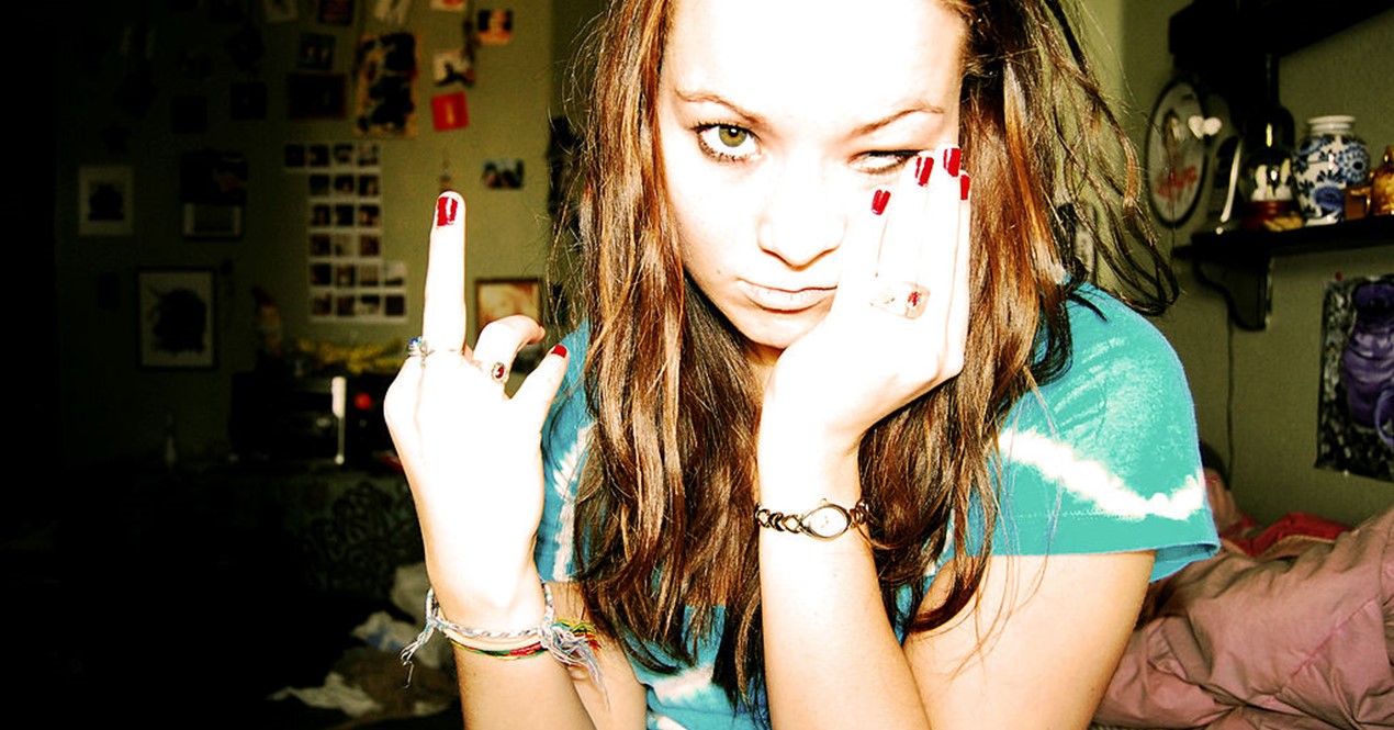 Ungdom i fokus på soverommet som viser fingeren og ser opprørt ut